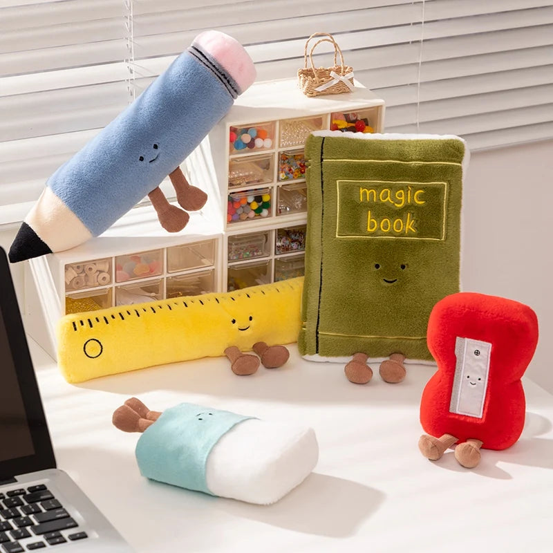 Colorful kawaii plush toys including a magic book, ruler, and heart on a desk with a laptop.