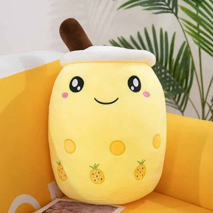 Plush toy shaped like a kawaii cartoon pineapple on a yellow couch with a plant in the background