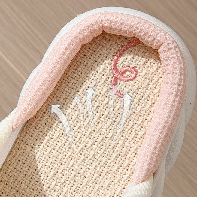 Close-up of a shoe with pink interior and embroidered kawaii design on a wooden floor.