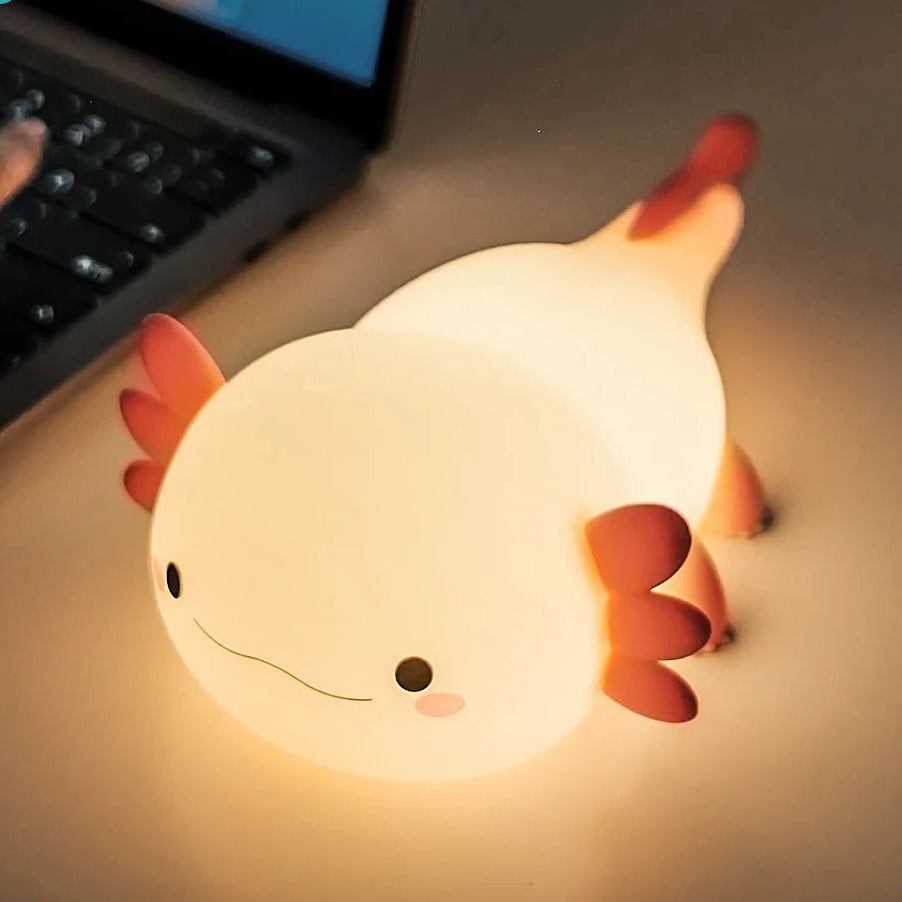 Kawaii axolotl-shaped night light on a desk next to a laptop