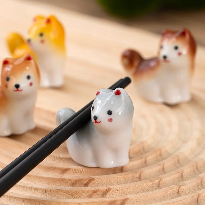 Ceramic kawaii animal-shaped chopstick rest on a wooden surface with other similar products in the background.