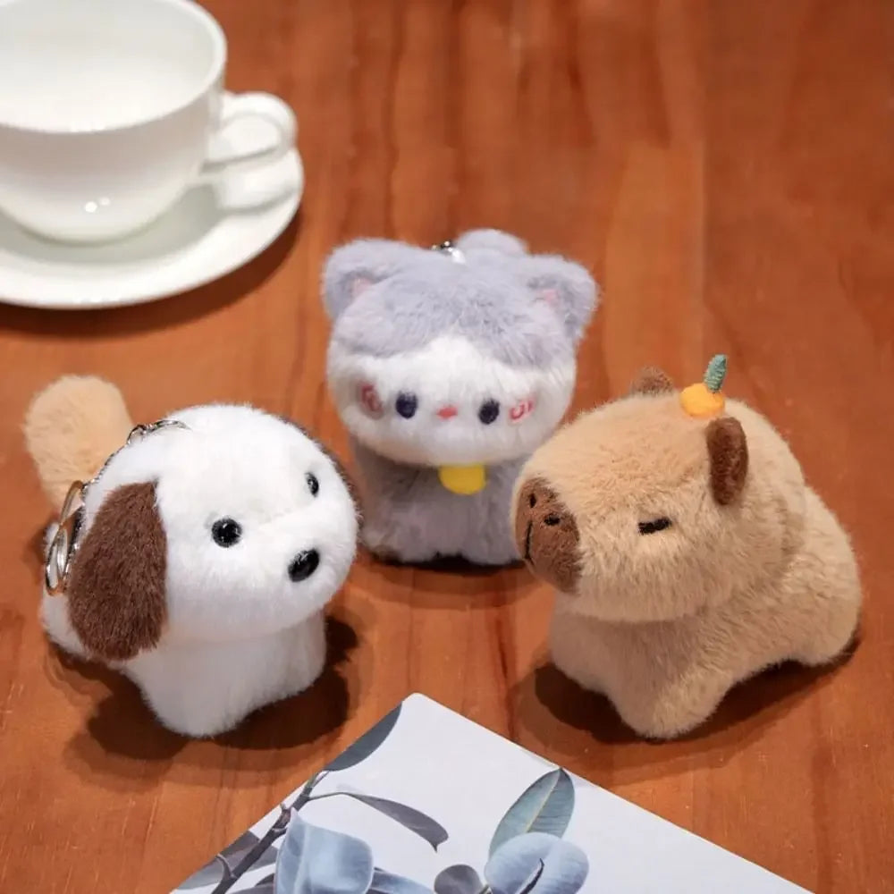 Three small kawaii plush toys on a wooden surface with a teacup in the background.