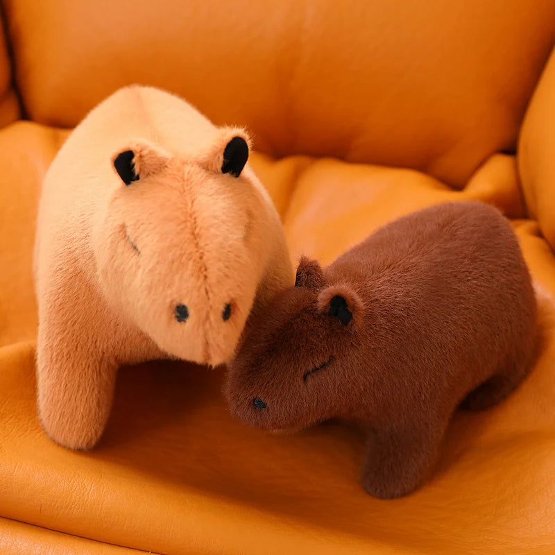Two kawaii plush animals, one pink and one brown, on an orange surface.