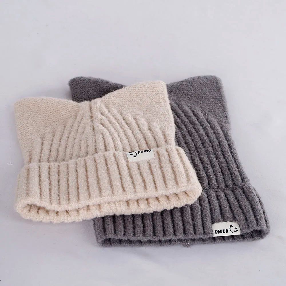 Two knit Kawaii beanies, one beige and one gray, with a brand label on a light gray background.