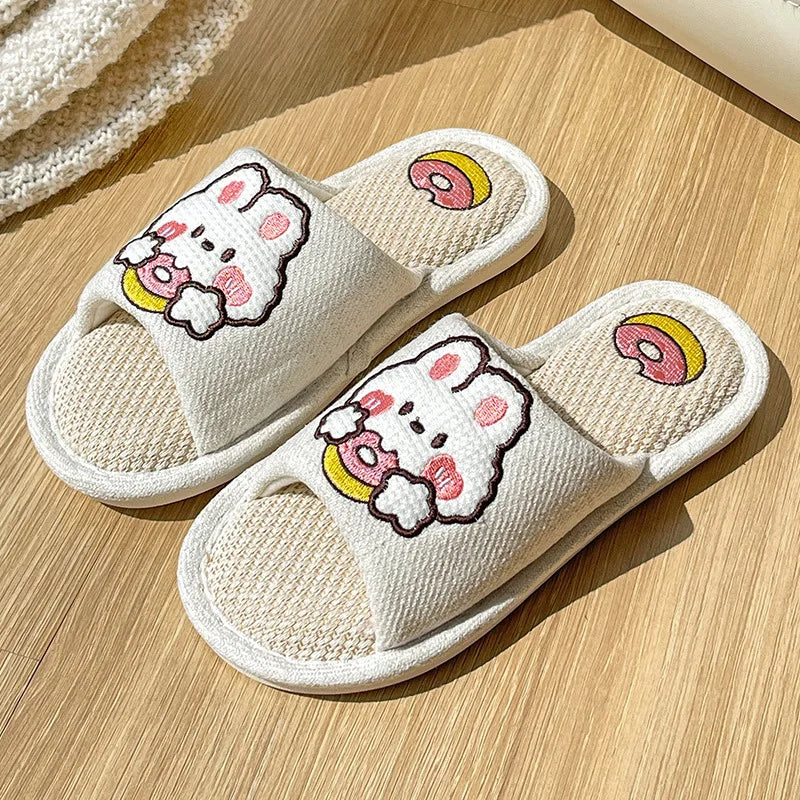 Pair of white slippers with kawaii cartoon character design on a wooden surface