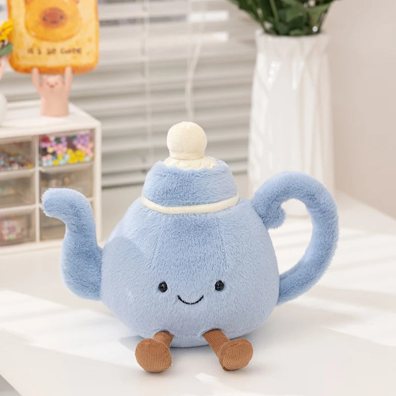 Blue plush teapot toy with a kawaii smiling face on a light surface.