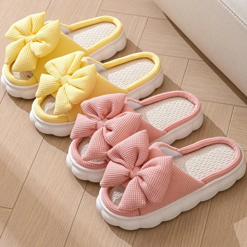 Yellow and pink slippers with kawaii bow details on a wooden floor.