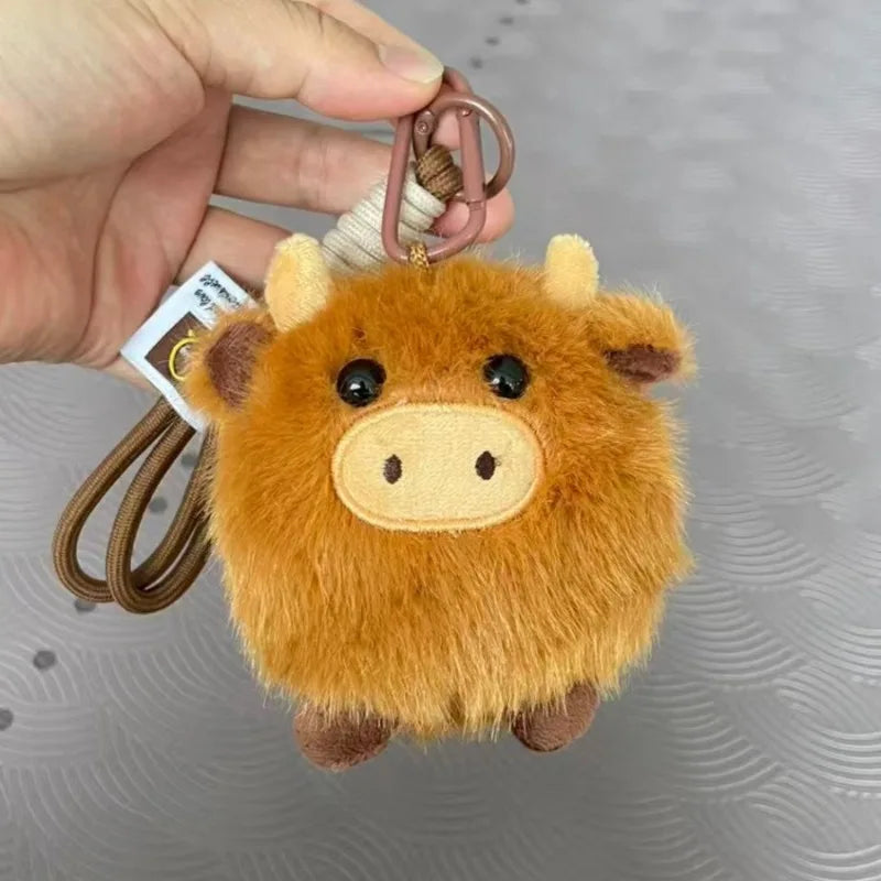 Plush kawaii cow keychain held by a hand with a gray background