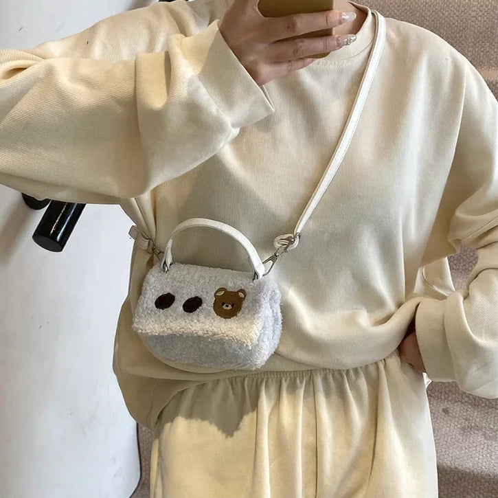 Person wearing a white dress holding a small white bag with Kawaii bear design.