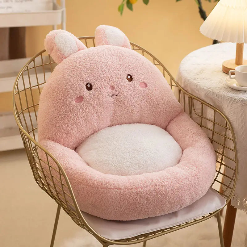 Pink plush kawaii cushion with bunny ears on a gold wire chair in a cozy room.