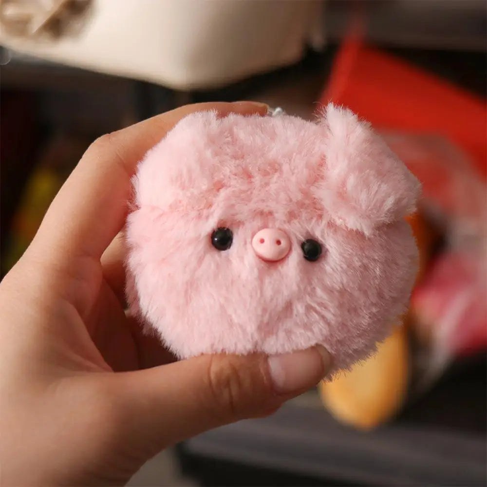 Small pink kawaii plush pig held in a hand with a blurred background