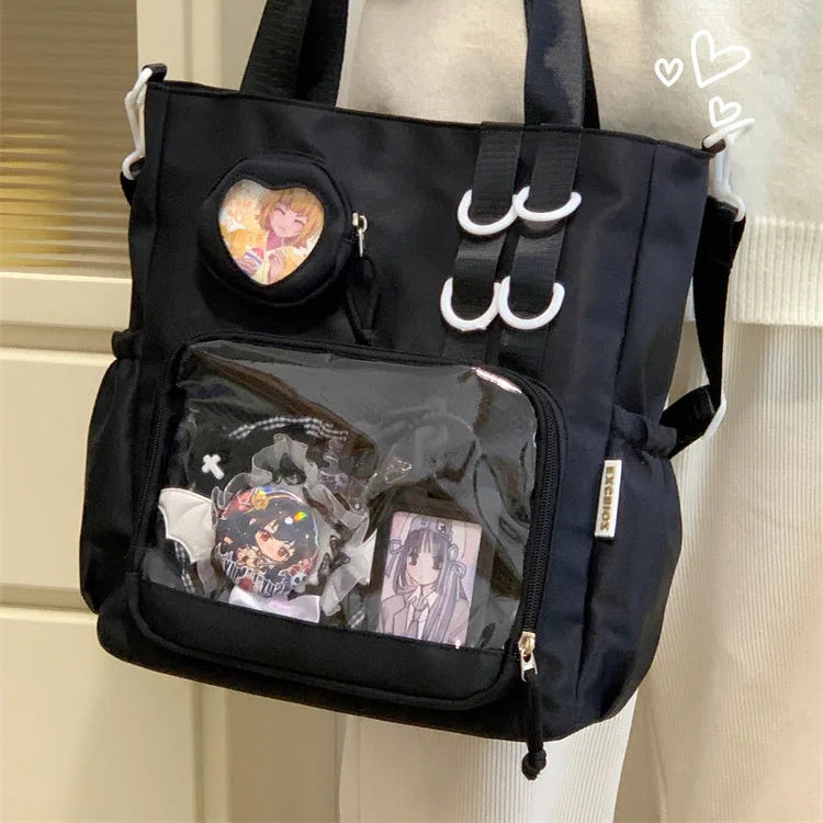 Black Kawaii handbag with transparent pocket and heart-shaped window held by a person wearing a white sweater.