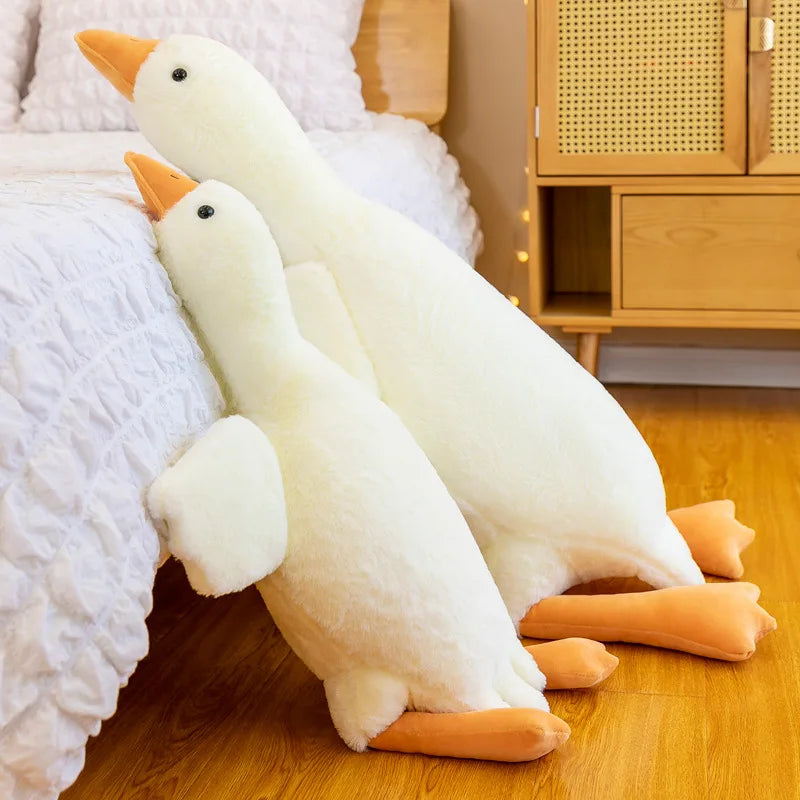 Two large white goose plush kawaii toys on a wooden floor.