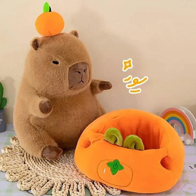 Kawaii plush bear with a pumpkin on its head and a matching orange pumpkin-shaped cushion on a textured surface.