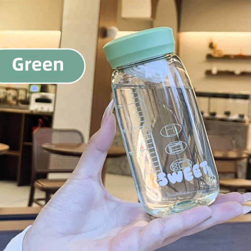 Clear Kawaii water bottle with green lid held by a hand in an indoor setting