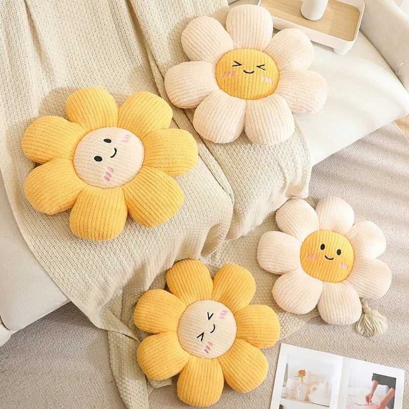 Three knitted flower-shaped kawaii cushions with smiling faces on a soft surface.