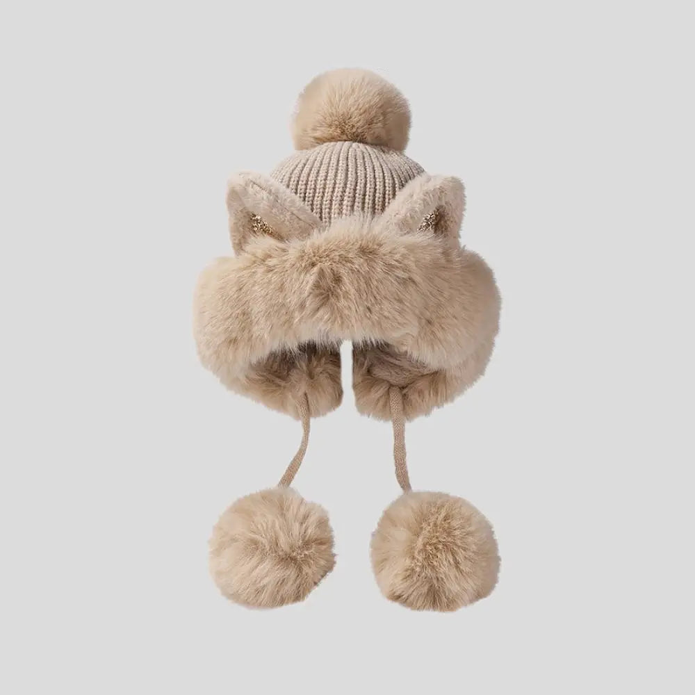 Beige knitted hat with faux fur accents and Kawaii pom-poms on a light gray background.