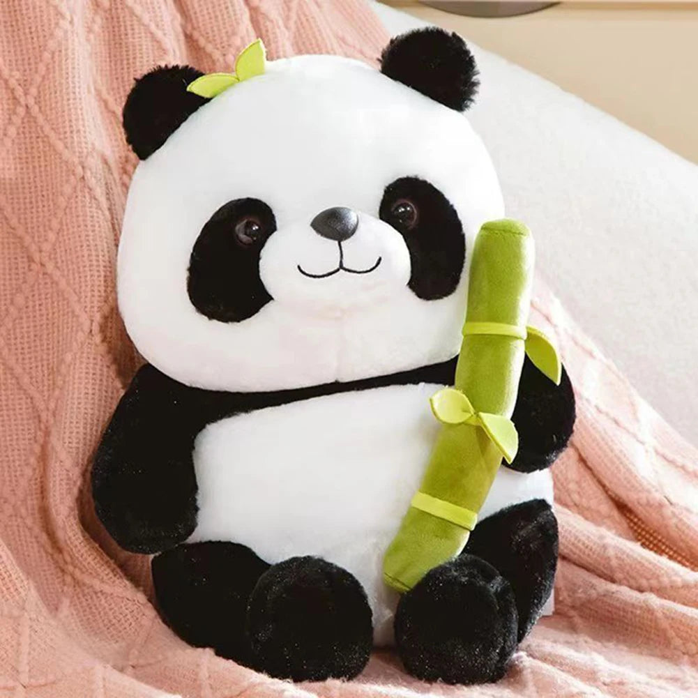 Plush kawaii panda toy holding a bamboo stick on a pink blanket