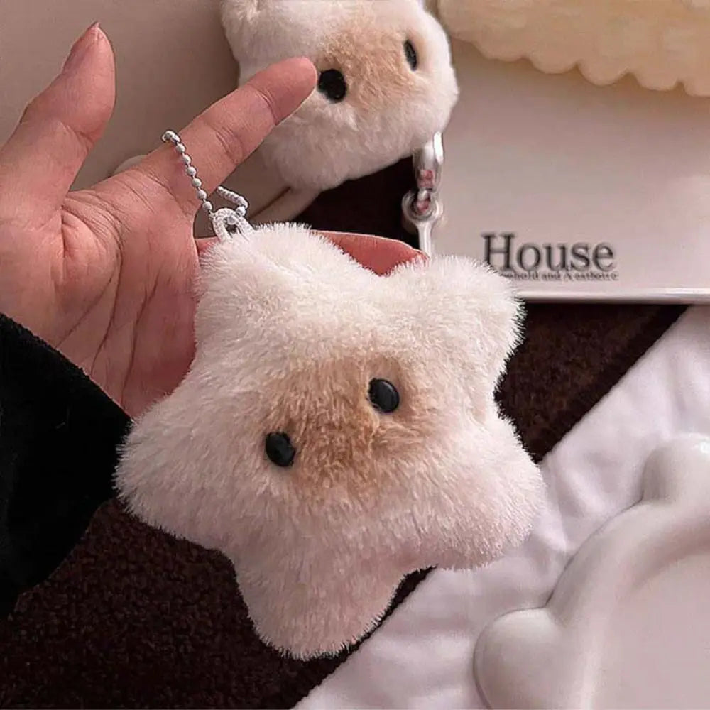 Plush keychain shaped like a kawaii bear held by a hand, with a blurred background.