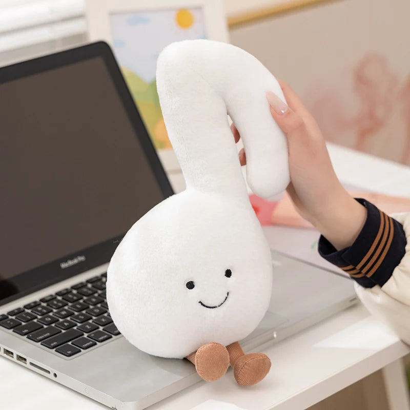 White plush swan kawaii toy held by a hand in front of a laptop on a desk.