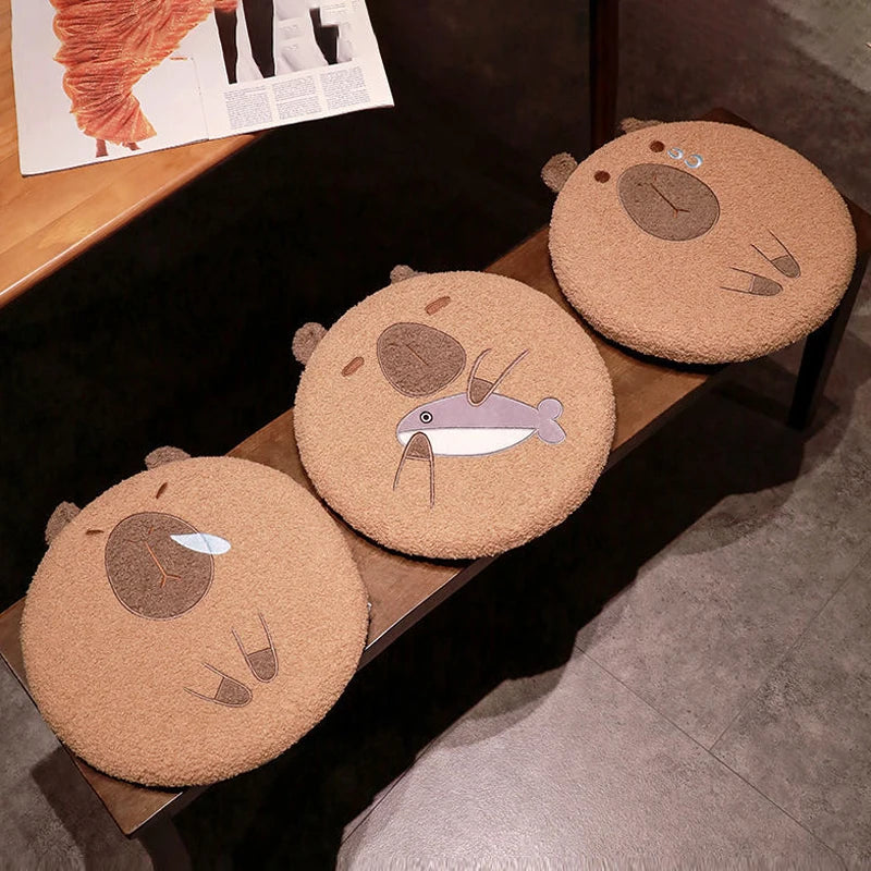 Three round capybara kawaii pillows with bear designs on a wooden surface.