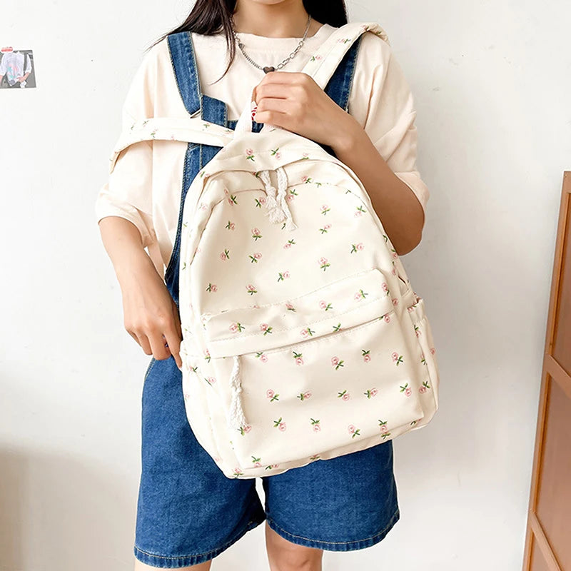 Person holding a Kawaii cream-colored backpack with floral patterns against a plain background
