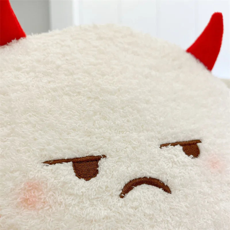 Close-up of a fluffy white kawaii plush toy with red horns and a sad expression.