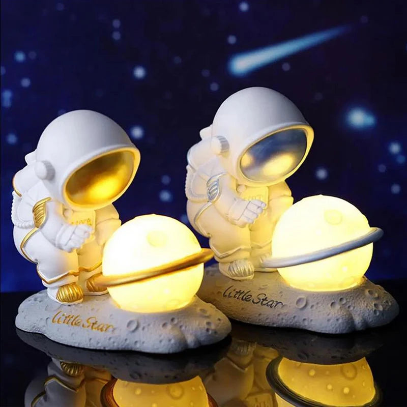 Two astronaut kawaii night lights on a reflective surface with a starry night background.