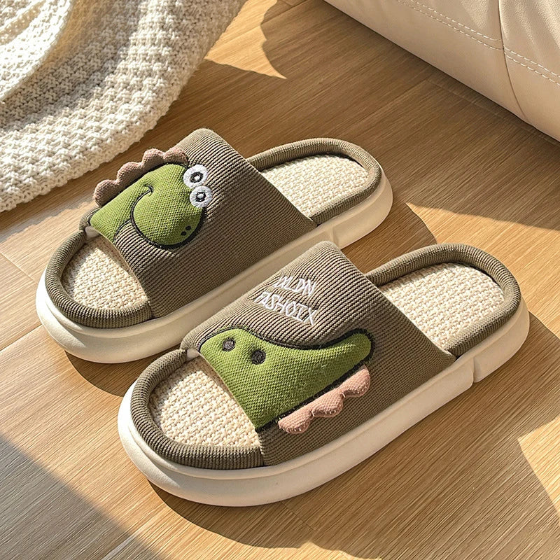 Pair of cartoon kawaii slippers with green frog design on a wooden floor.