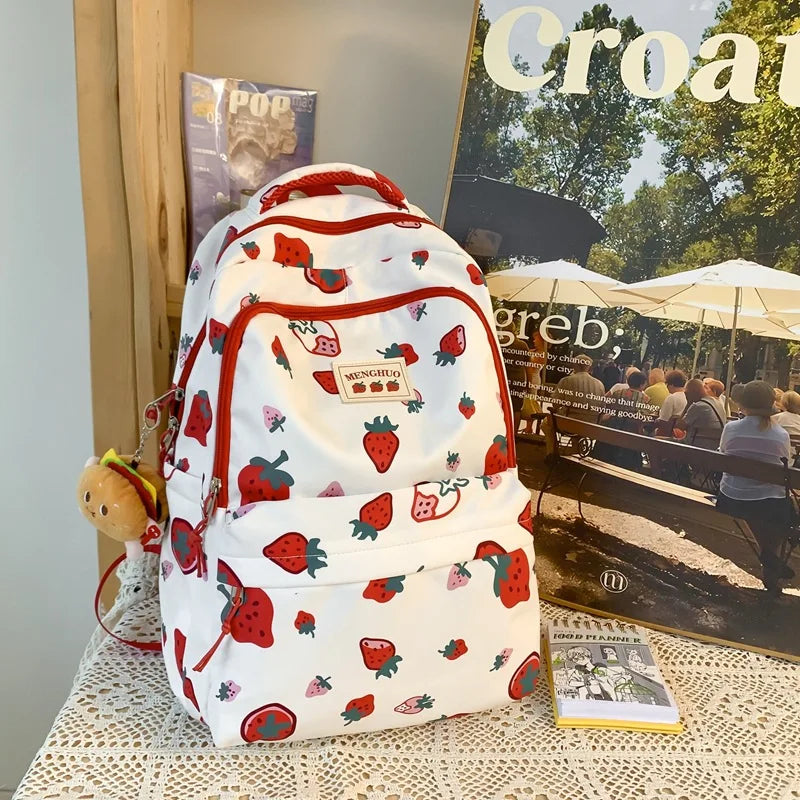 Kawaii backpack with strawberry pattern on a table with magazines in the background