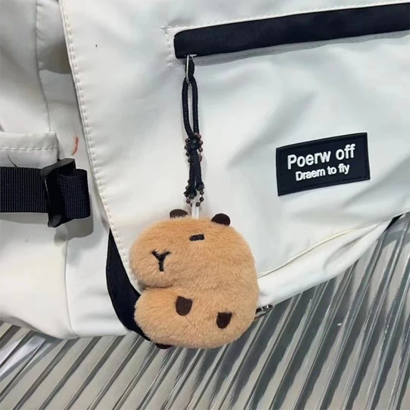 Plush kawaii keychain attached to a white backpack with a visible brand label.