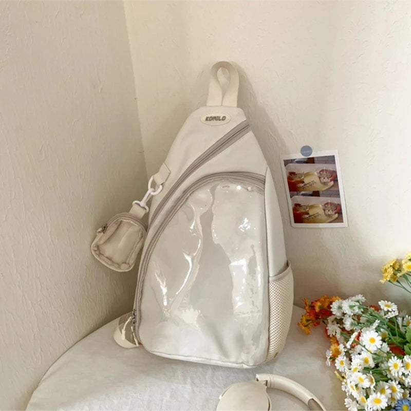 White Kawaii sling bag with clear front pocket on a white surface with flowers and a photo in the background