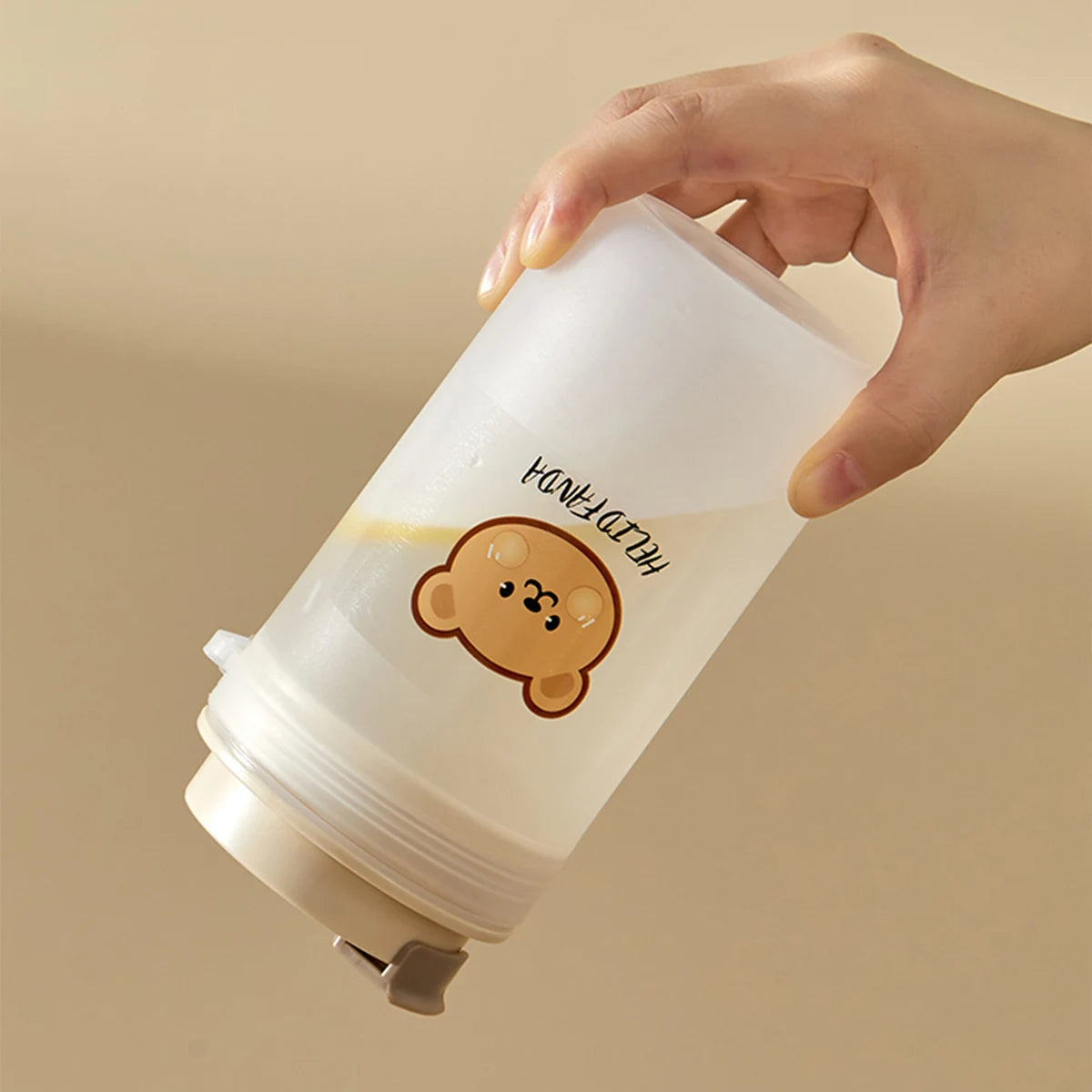 Hand holding a white container with a Kawaii cartoon monkey design and text on a beige background