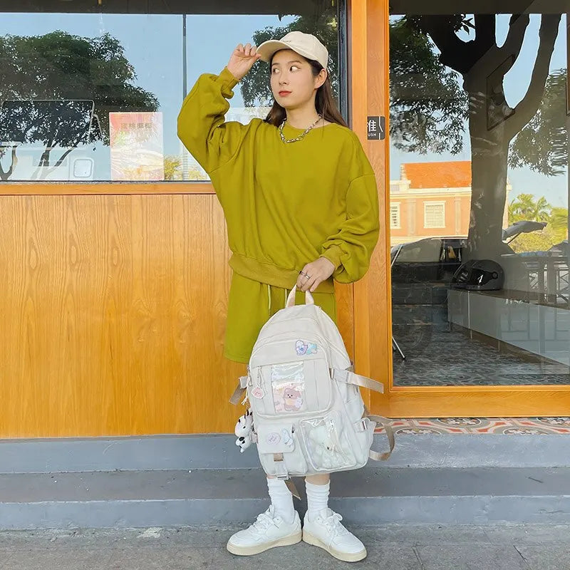 Person wearing a Kawaii green outfit with a white backpack in front of a building.