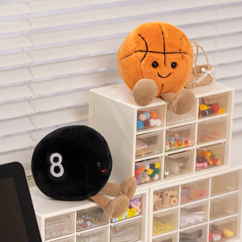 Plush kawaii toys resembling a basketball and a pool ball on a shelf with transparent drawers.