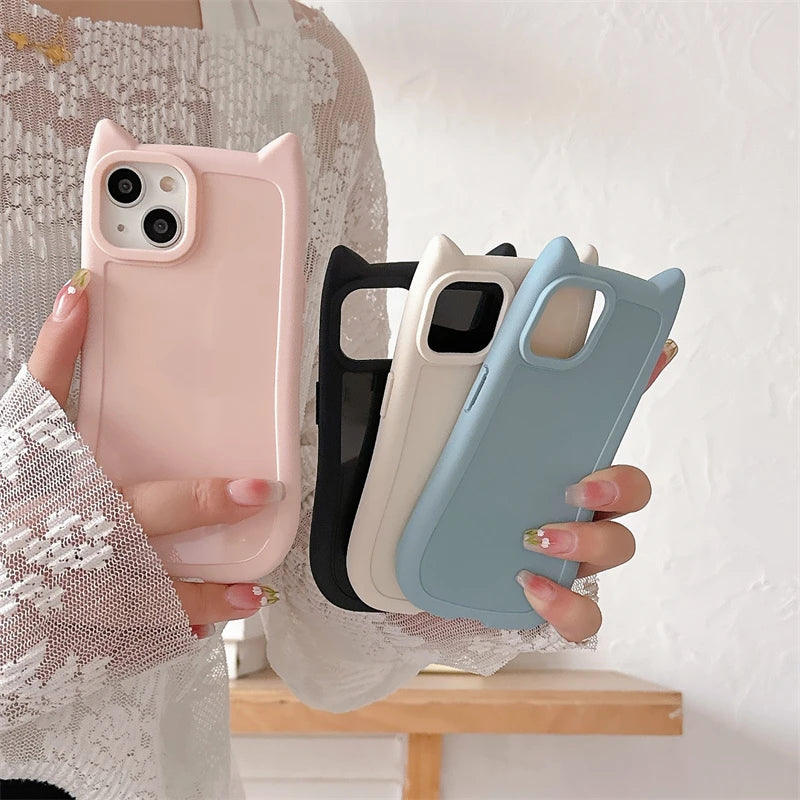 Four kawaii phone cases in pink, black, white, and blue held by a person against a neutral background.