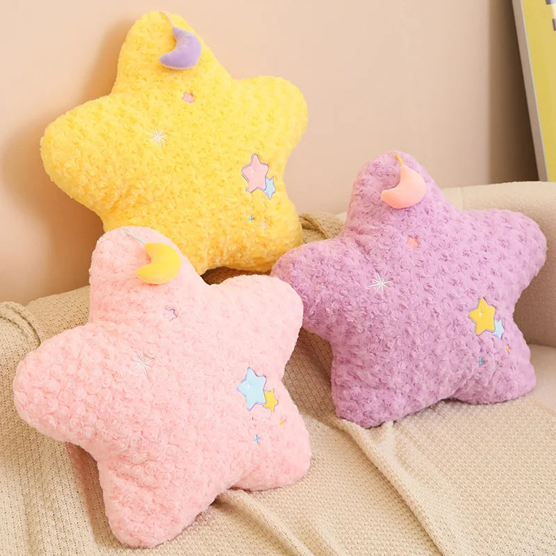 Three star-shaped kawaii cushions in yellow, pink, and purple on a beige couch.