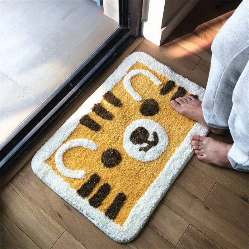 Doormat with Kawaii cat design on a wooden floor next to a glass door.