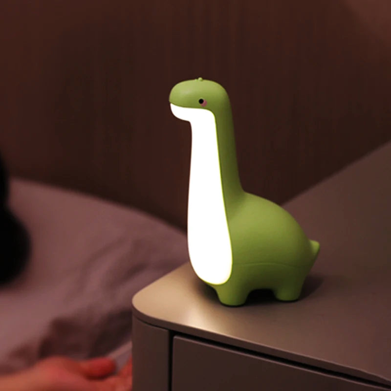 Green dinosaur-shaped kawaii night light on a surface with a blurred background