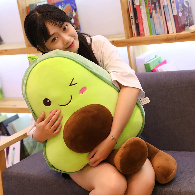 Person holding a kawaii plush avocado toy in a cozy room with books on shelves.