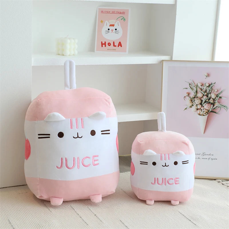 Two pink and white kawaii plush toys shaped like cats with 'JUICE' text on a light wooden floor.