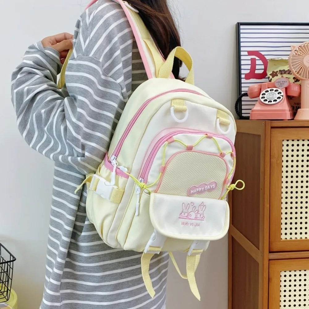 Person wearing a Kawaii light yellow backpack with pink accents indoors.