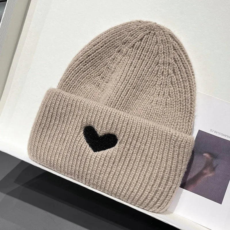 Beige knit Kawaii beanie with a black heart on a white surface