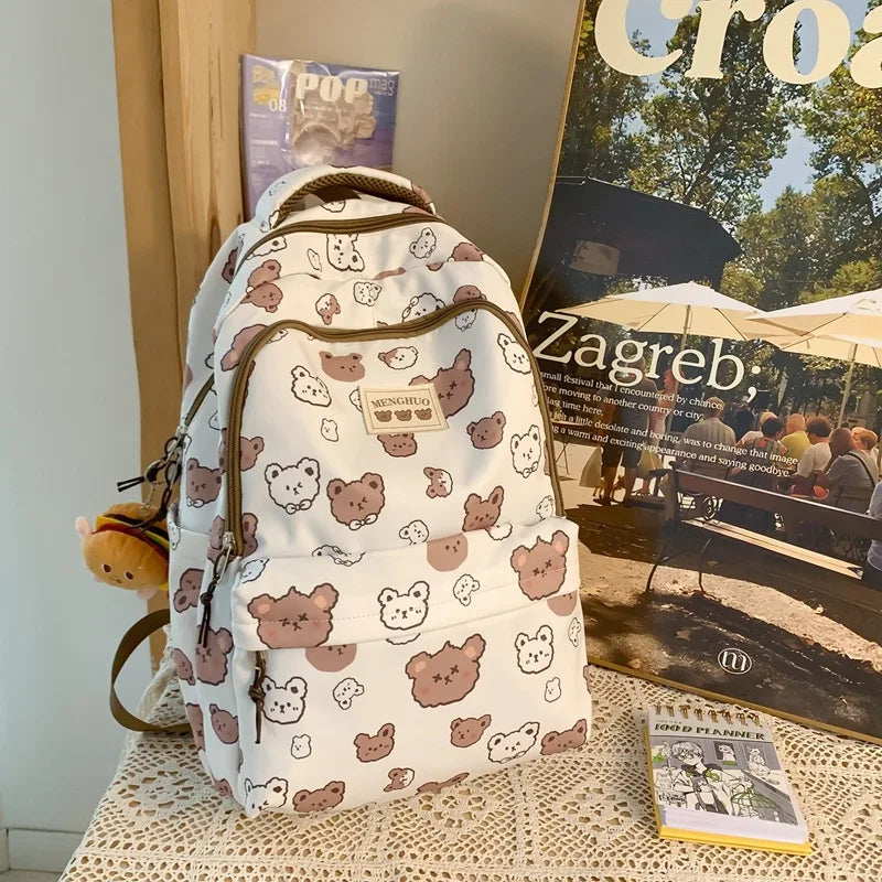 Kawaii designed backpack with bear pattern on a table with magazines and a book in the background