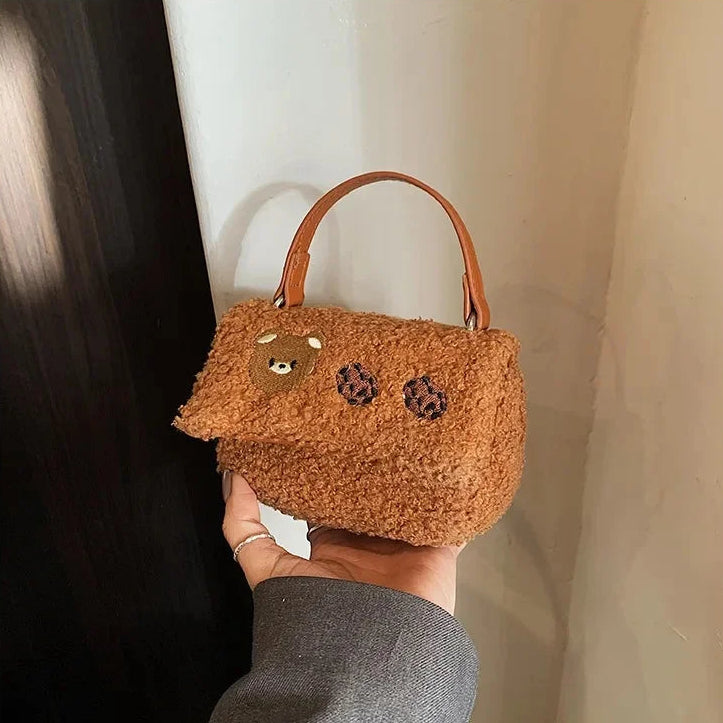 Brown Kawaii teddy bear-shaped handbag held by a person against a neutral background