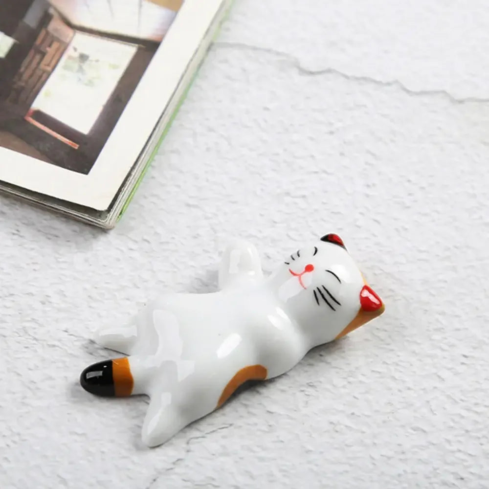 White kawaii cat-shaped stress reliever toy on a textured surface with a book in the background