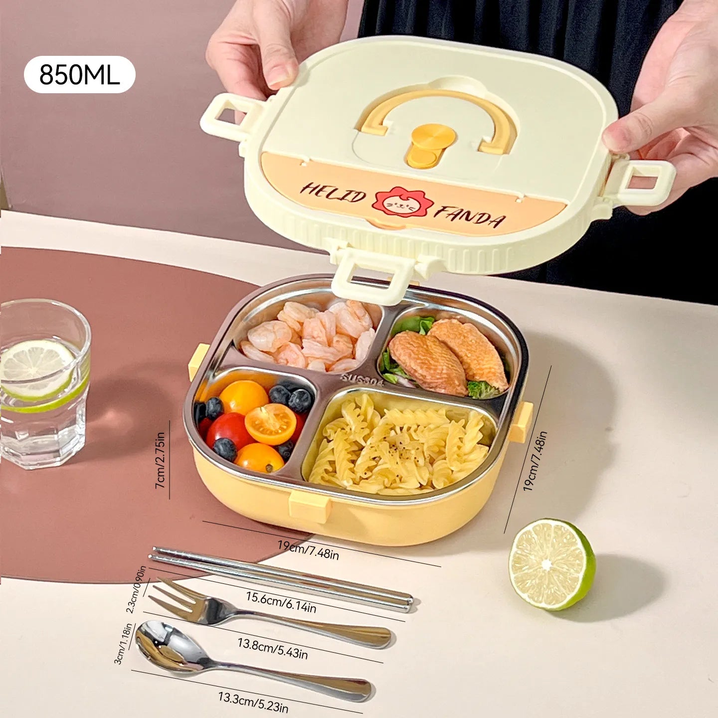 Children's kawaii lunch box with compartments filled with food, a glass of water, and utensils on a table.