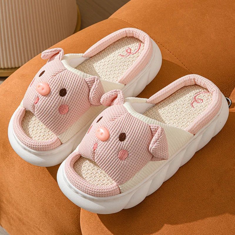 Pair of pink kawaii animal-themed slippers on a brown surface