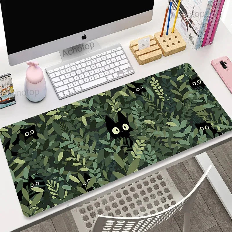 Desk setup with a Kawaii green leafy desk mat featuring black cat illustrations.