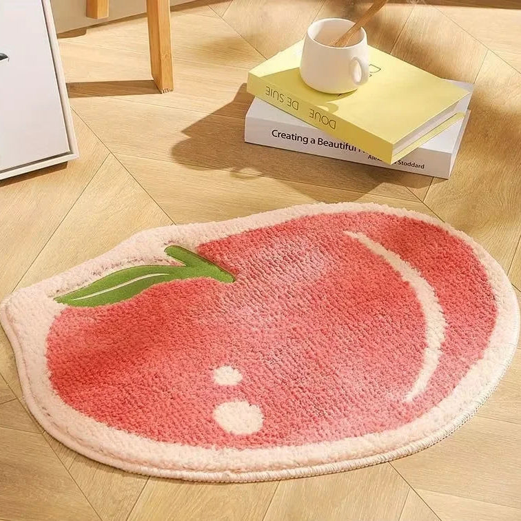 Pink Kawaii apple-shaped rug on a wooden floor with books and a mug.